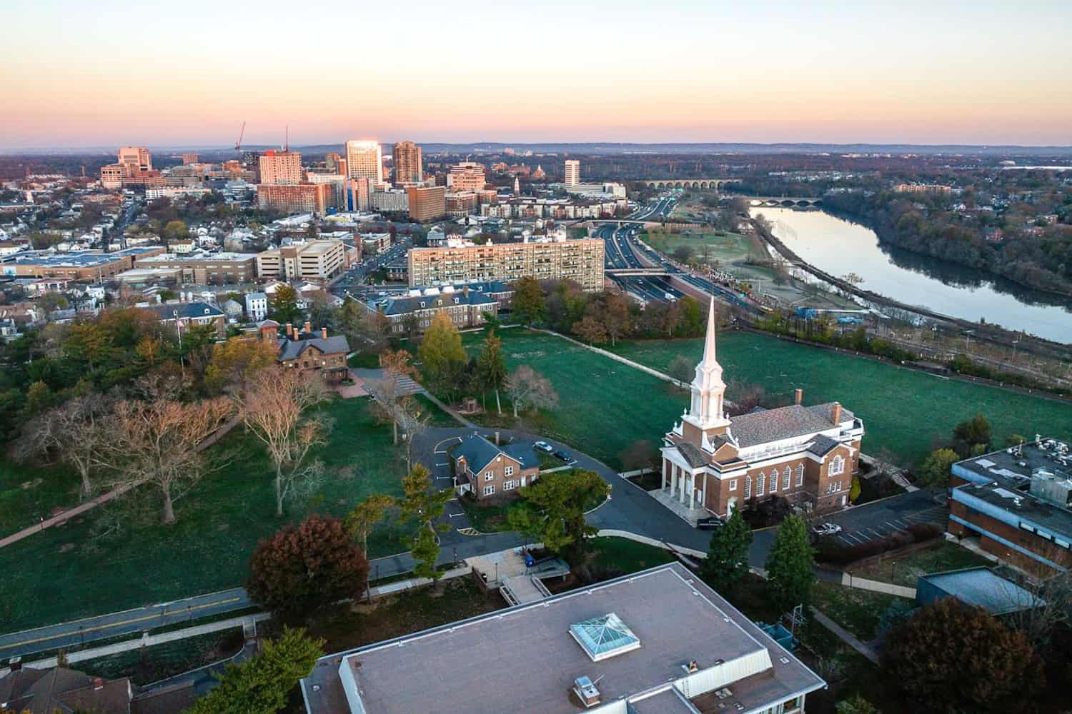 Drone view of downtown New Brunswick, Rutgers campus buildings, and the Raritan River at sunrise in Central New Jersey.