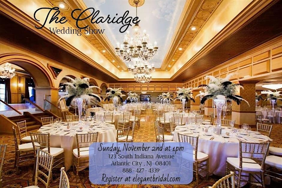 Elegant ballroom at The Claridge Hotel set with round tables, tall floral centerpieces, and chandeliers for a wedding show.