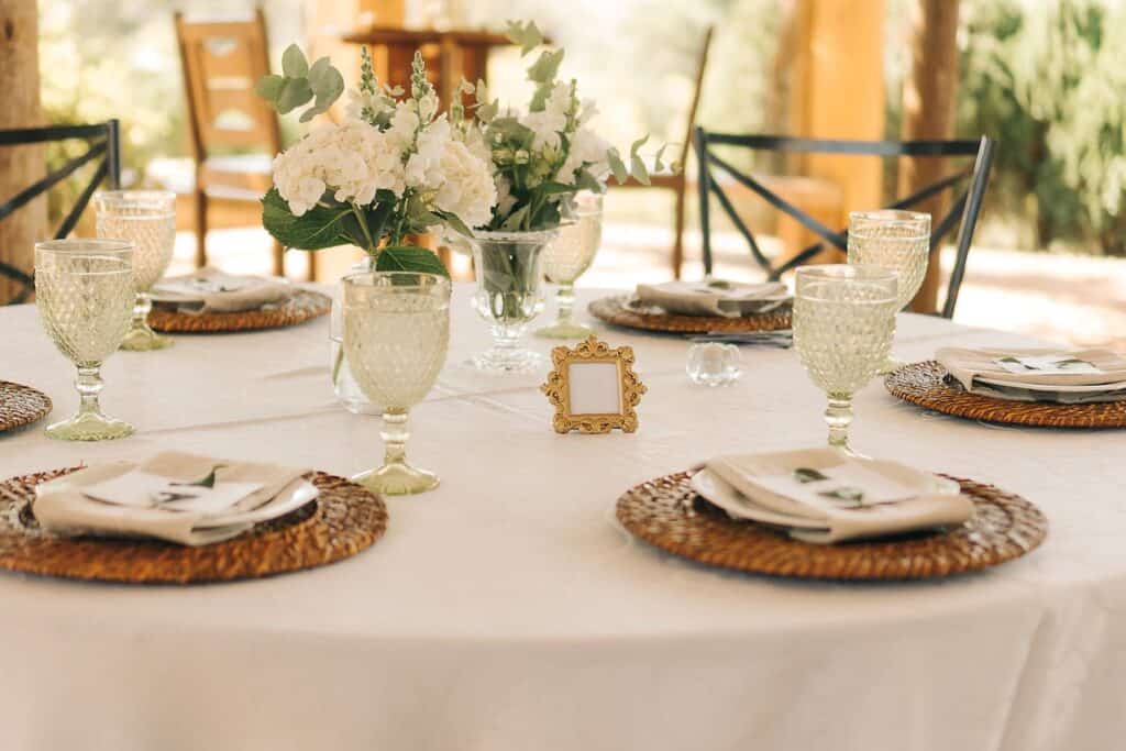 Elegant budget-friendly New Jersey wedding table with simple floral centerpieces, candles, and rustic woven chargers.
