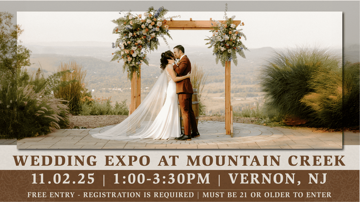 Bride and groom share a kiss beneath a wooden floral arch overlooking a scenic mountain view at Mountain Creek Resort in Vernon, NJ.