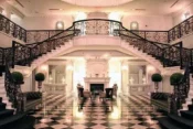 Elegant grand staircase inside Addison Park with marble floors, ornate railings, and glowing chandeliers — a sophisticated wedding venue.