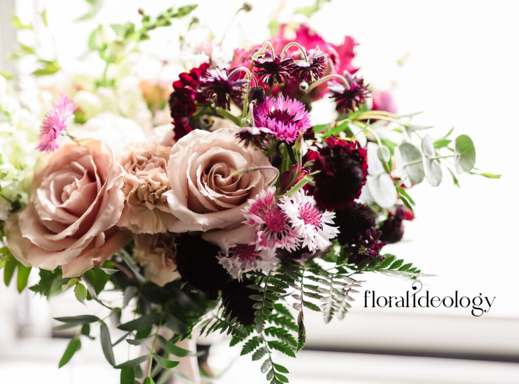 Wedding bouquet with blush roses, burgundy blooms, and textured greenery by Floral Ideology in Wayne, New Jersey