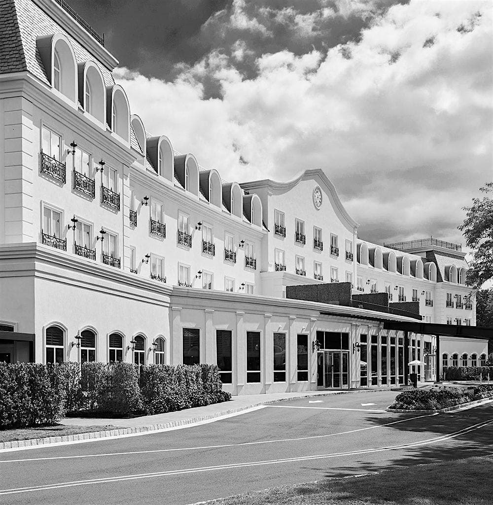 Black and white photo of the Chateau Grande Hotel in East Brunswick, NJ, showing elegant French-style architecture with mansard roof and landscaped entrance