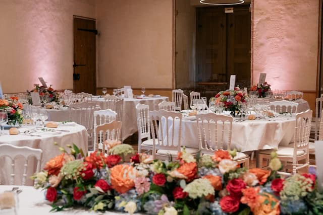 Elegantly set wedding reception venue with round tables, white linens, and colorful floral centerpieces, representing New Jersey wedding costs for a full-service venue experience.